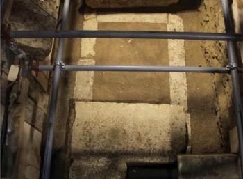 Σε βάθος 1,60μ. από τους σωζόμενους λίθους του δαπέδου, αποκαλύφθηκε μεγάλος κιβωτιόσχημος τάφος, κατασκευασμένος από πωρόλιθους.